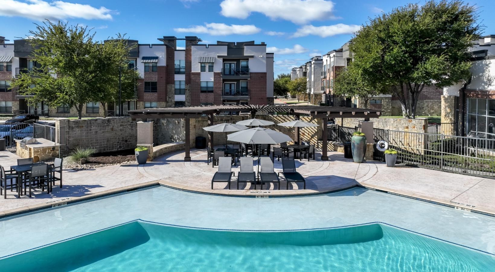 Relax and unwind poolside a pool with umbrellas and chairs by a building