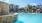 a pool with a stone wall and buildings in the background